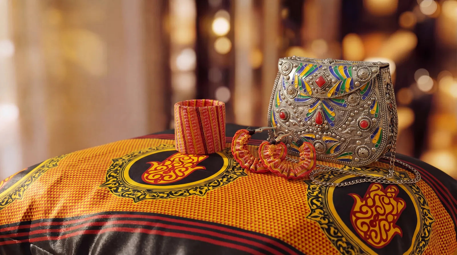 Pochette Malali en métal émaillé et bijoux kardoun sur un tissu kabyle